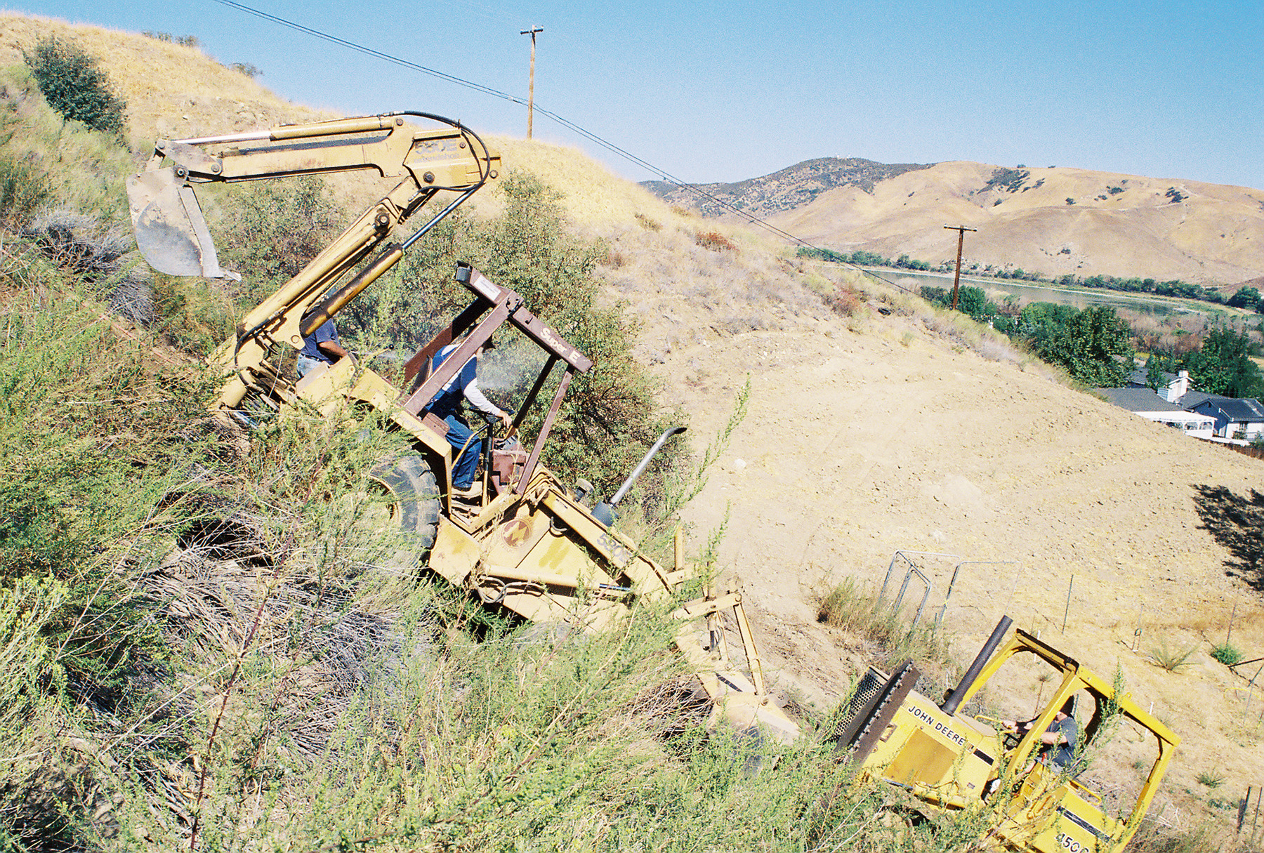 Dozer pushing Backhoe up hill for repairs